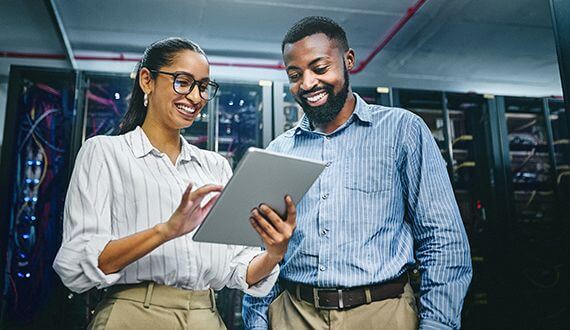 two professionals looking at a tablet with an enterprise grade scalable data center in the background